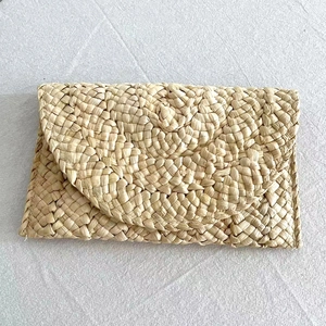 Macro detail of natural straw woven texture and artisan spiral stitching on envelope clutch