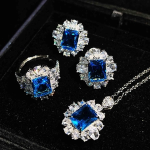 Elegant jewelry set with blue square gemstones and diamonds including ring, earrings, and necklace