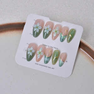Detail of emerald green ombre press-on nails with 3D floral accents and gold star art
