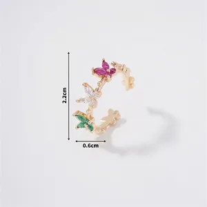 Detail view of a gold butterfly ring featuring pink, white, and emerald green zircons