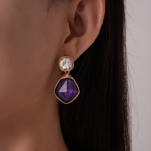 Dettaglio di modella che indossa orecchini in resina geometrici viola e trasparenti
