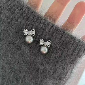Détail macro de boucles d'oreilles nœud argenté avec zircons et perle grise
