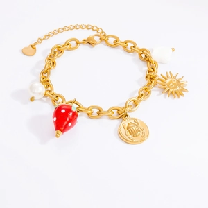 Detail of gold chain bracelet featuring strawberry charm and sun pendant on white background