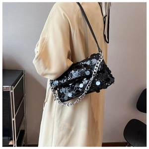 Detail of elegant black sequin shoulder bag with silver metal chain on female model