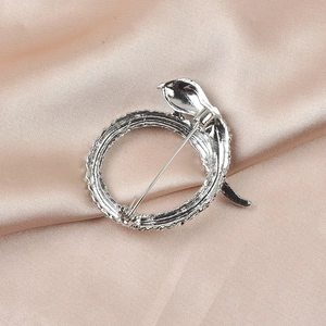 Detailed close-up of a silver snake-shaped brooch on elegant pink silk fabric