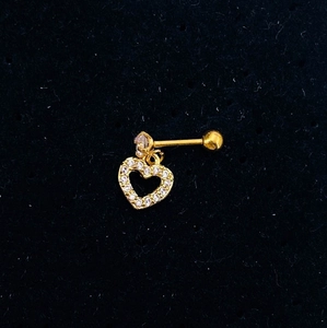 Macro detail of gold heart-shaped stud earring with cubic zirconia on black velvet background