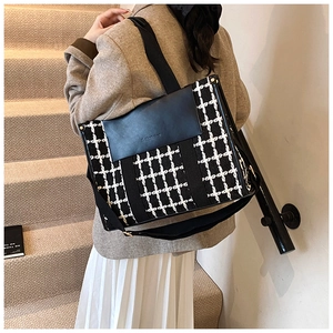 Detail of black faux leather and houndstooth tote bag worn with a stylish blazer