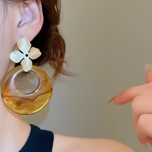 Detail of amber resin ring drop earrings with gold floral studs on a fashion model