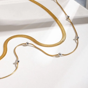 Dettaglio collana a strati con catena a serpente dorata e perline d'argento donna