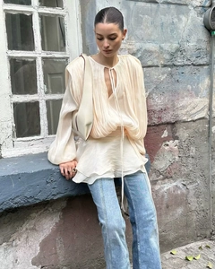 Detailed close-up of beige sheer pleated puff sleeve top with drawstring neckline design