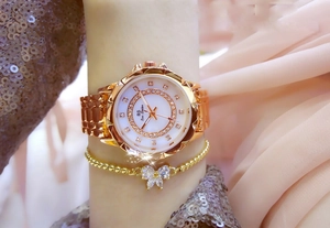 Close-up of rose gold watch and butterfly bracelet on pink silk with sparkling effects