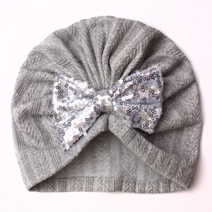 Detailed top view of a grey knit baby turban hat with a shiny silver sequin bow