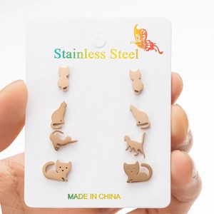 Detailed view of four pairs of rose gold cat-shaped stainless steel stud earrings on card