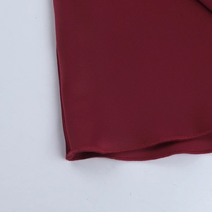 Detailed close-up showing fine stitching and hem work on a burgundy backless evening dress