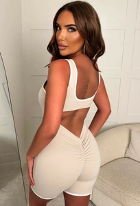 Detail of beige backless yoga jumpsuit with white trim and ruched butt design on back