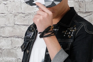 Detail of men's multi-layered black leather bracelet with a gold hook clasp on wrist