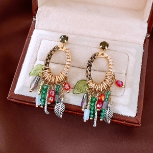 Close-up of ethnic beaded tassel earrings with crystal beads and leaf charms in a jewelry box