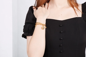 Close-up of golden double-layer chain bracelet featuring a sun pendant on model wrist