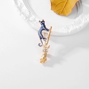 Détail de la broche chat bleu sur balai doré avec strass sur cadre blanc élégant