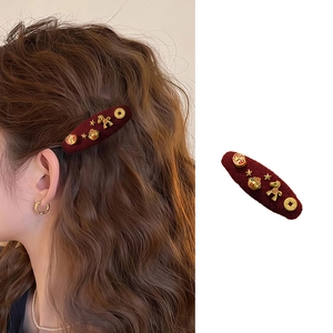 Detail view of a vintage red flocked hair clip with gold horse and lucky coin charms