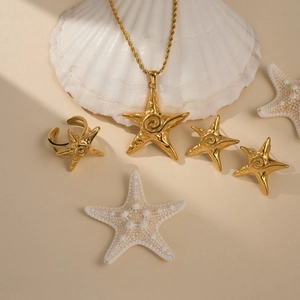 Golden starfish jewelry set with necklace ring and earrings on decorative white shells