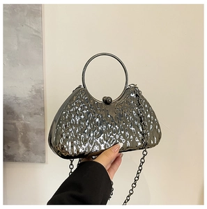 Detail of evening bag with hammer-textured metallic surface and round ring handle