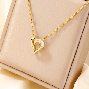 Golden heart pendant necklace with zircon stones on a beige jewelry display box