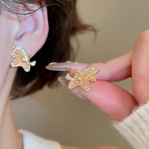 Macro detail of 18k gold plated unicorn stud earring with sparkling champagne zircon