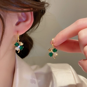 Detail of clover earring with green and white zircons worn on ear for elegant style