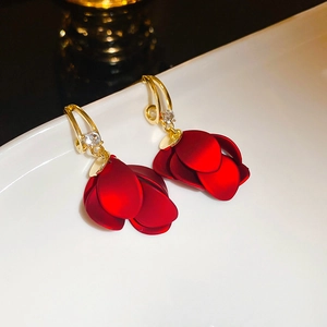 Macro shot of red matte petal earrings with gold hooks and sparkling zircon accents