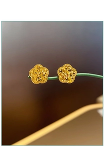 Makroaufnahme goldener Blumenohrringe mit matter Glitzertextur auf grünem Stiel