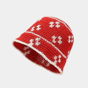 Detail of red handmade crochet bucket hat featuring intricate white floral knitting patterns