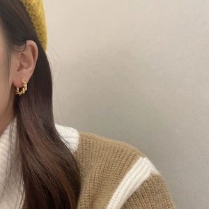 Golden twisted hoop earrings with elegant spiral texture worn by a female model