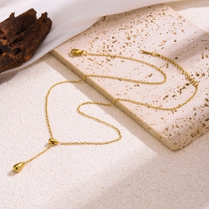 Collier minimaliste avec pendentif goutte d'eau dorée sur fond en pierre texturée
