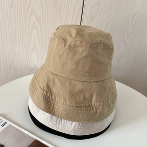 Foldable cotton bucket hats for women in khaki, white, and black colors stacked on table