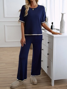 Detail of dark blue knit lounge set with cream contrast trim on short sleeves and wide legs