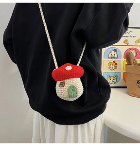 Close-up of handmade knitted crossbody bag in creative red mushroom house shape design