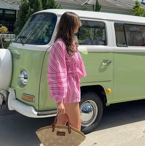 Ensemble d'été à rayures roses et sac en paille marguerite devant un van rétro pour les vacances