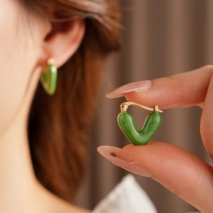Detailed view of vintage green enamel V-shaped hoop earrings with gold metal needles