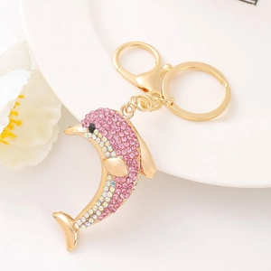 Detail of a golden dolphin keychain with pink rhinestones on a decorative white dish