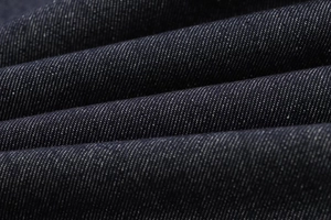 Macro detail of high-density dark indigo denim fabric with cotton slub texture