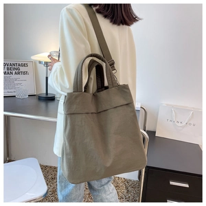Army green large nylon tote bag with pleated texture shown from side-back on model