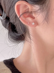 Close-up of minimalist 925 sterling silver flower and bead stud earrings on ear