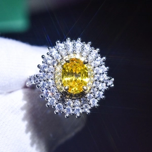 Macro shot of a platinum plated ring with a large oval yellow gemstone and halo diamonds