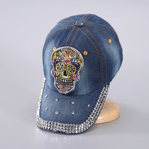 Broderie détaillée d'un crâne avec strass et clous métalliques sur casquette en denim bleu