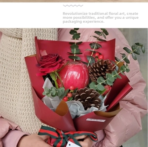 Detail of Christmas bouquet with red rose, apple, pine cone and festive ribbon wrap