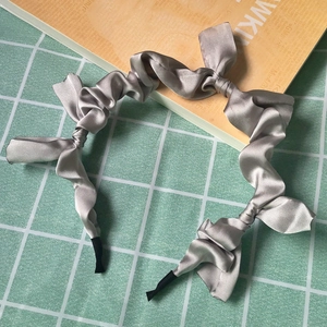 Detail of grey satin headband with multiple bow knots on a green grid background