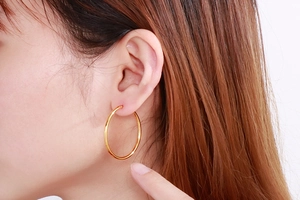 Close-up of a model wearing a large polished golden 304 stainless steel hoop earring
