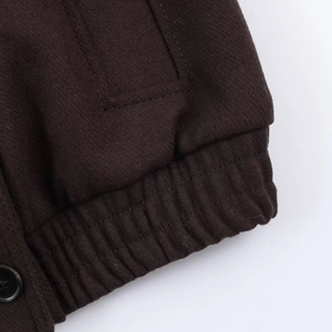 Détail d'un manteau en laine marron foncé montrant l'ourlet côtelé et le bouton