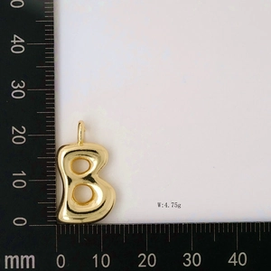 Size and weight detail of golden bubble letter B pendant showing 4.75g mass on a metric scale